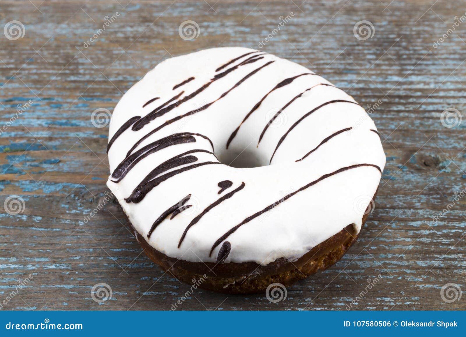 white glazed donut with chocolate stripes on wooden background