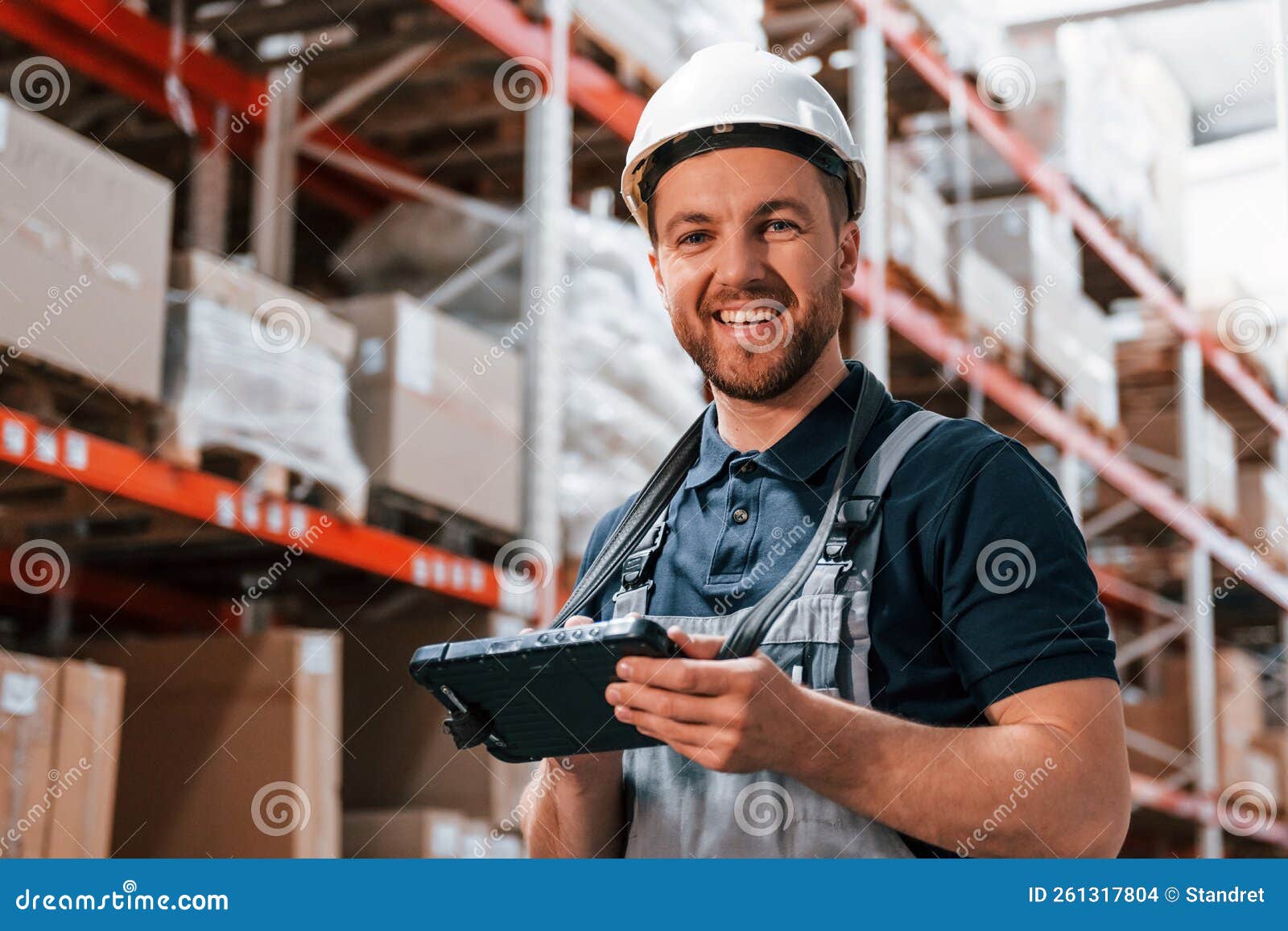 In White Hard Hat and with Tablet. Employee in Uniform is Working in