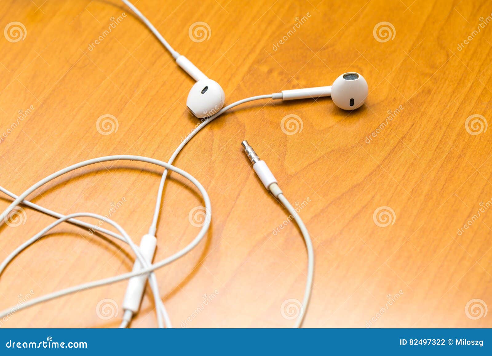 Close up of white headphones lying on wooden table. Small white earphones.