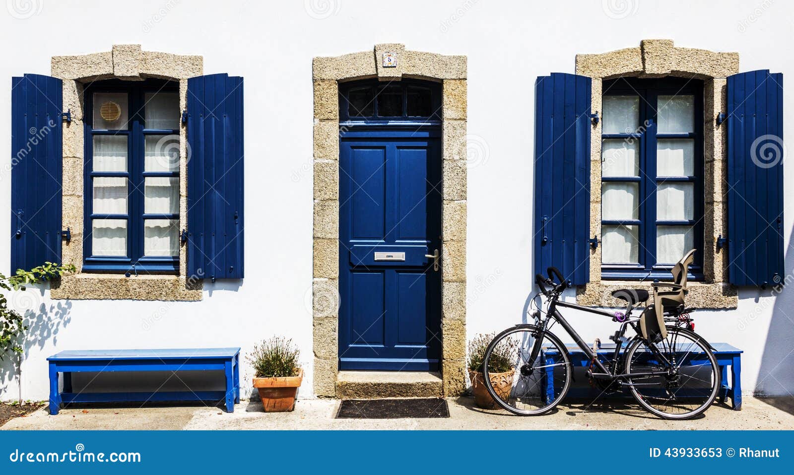 white country house with blue windows, door and bench.