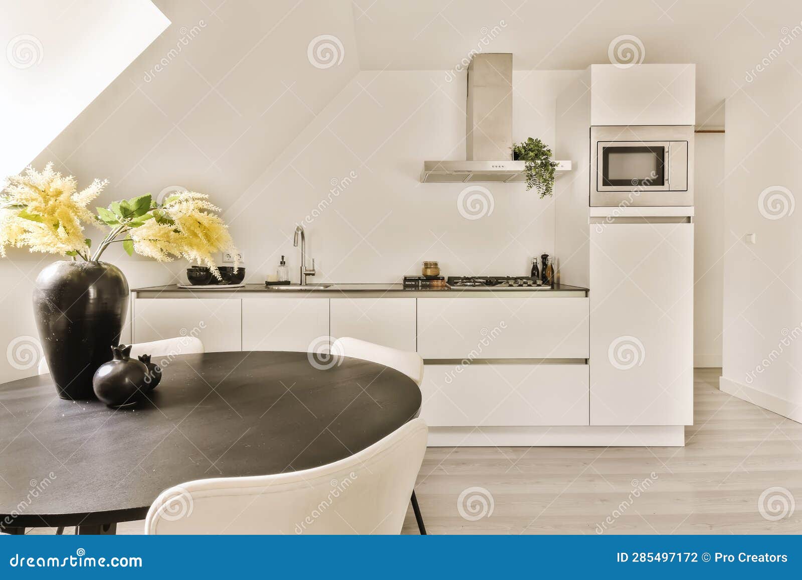 A White Kitchen with a Black Table and White Chairs Stock Photo Image