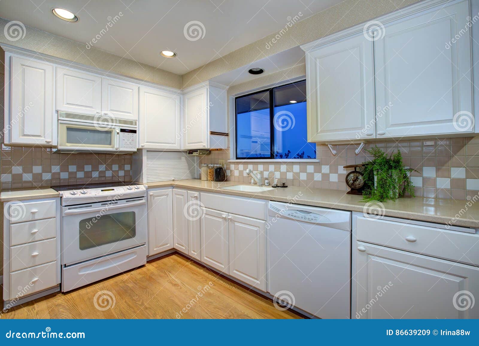 White Kitchen Design With Hardwood Floor And White Appliances