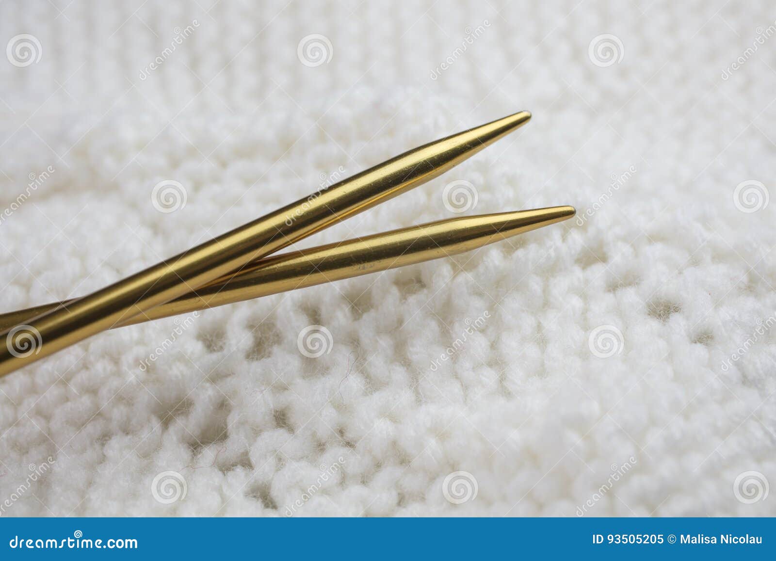 White Knitted Garment with Gold Colored Knitting Needles Stock Image