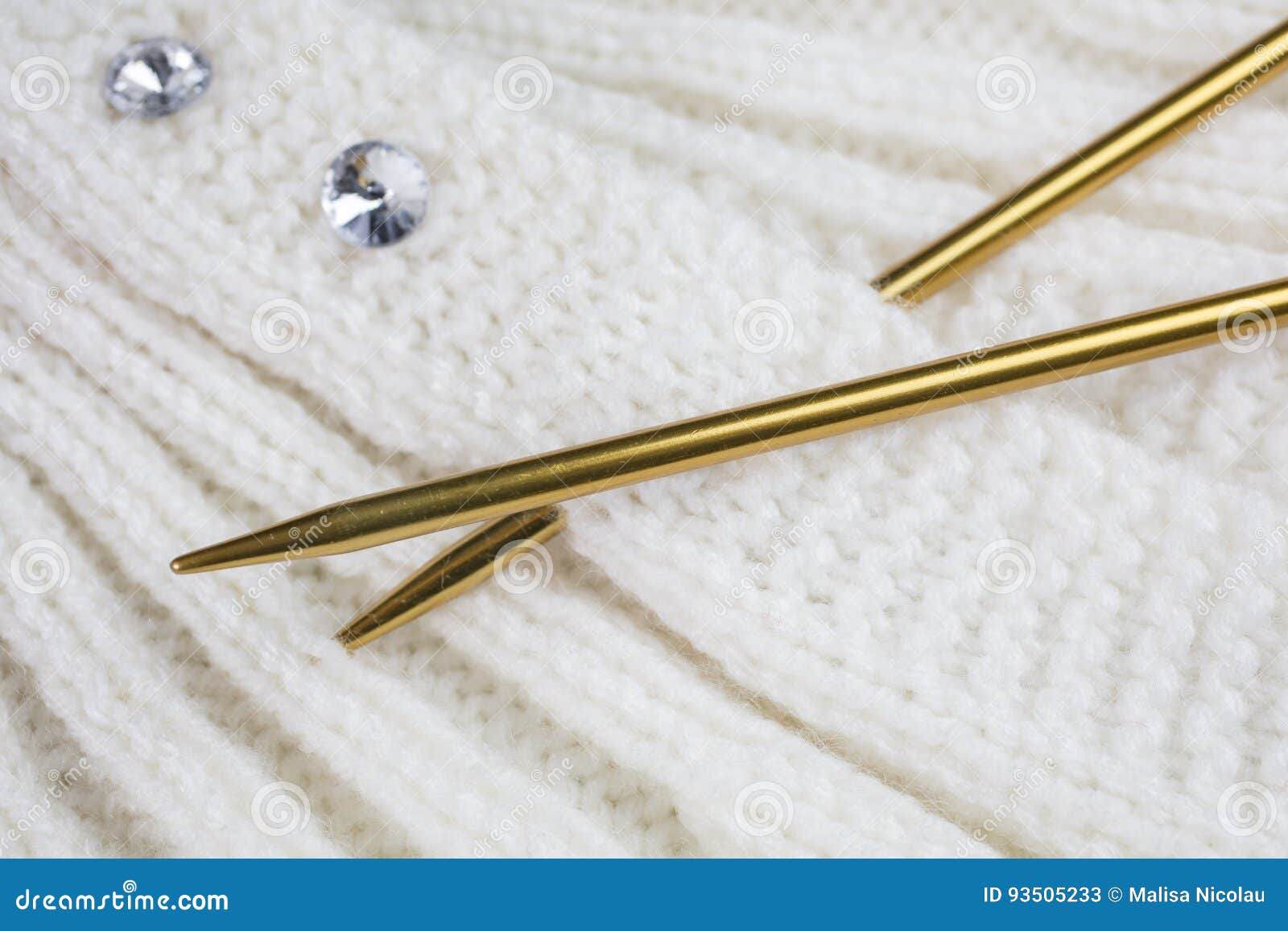 White Knitted Garment with Gold Colored Knitting Needles Stock Image