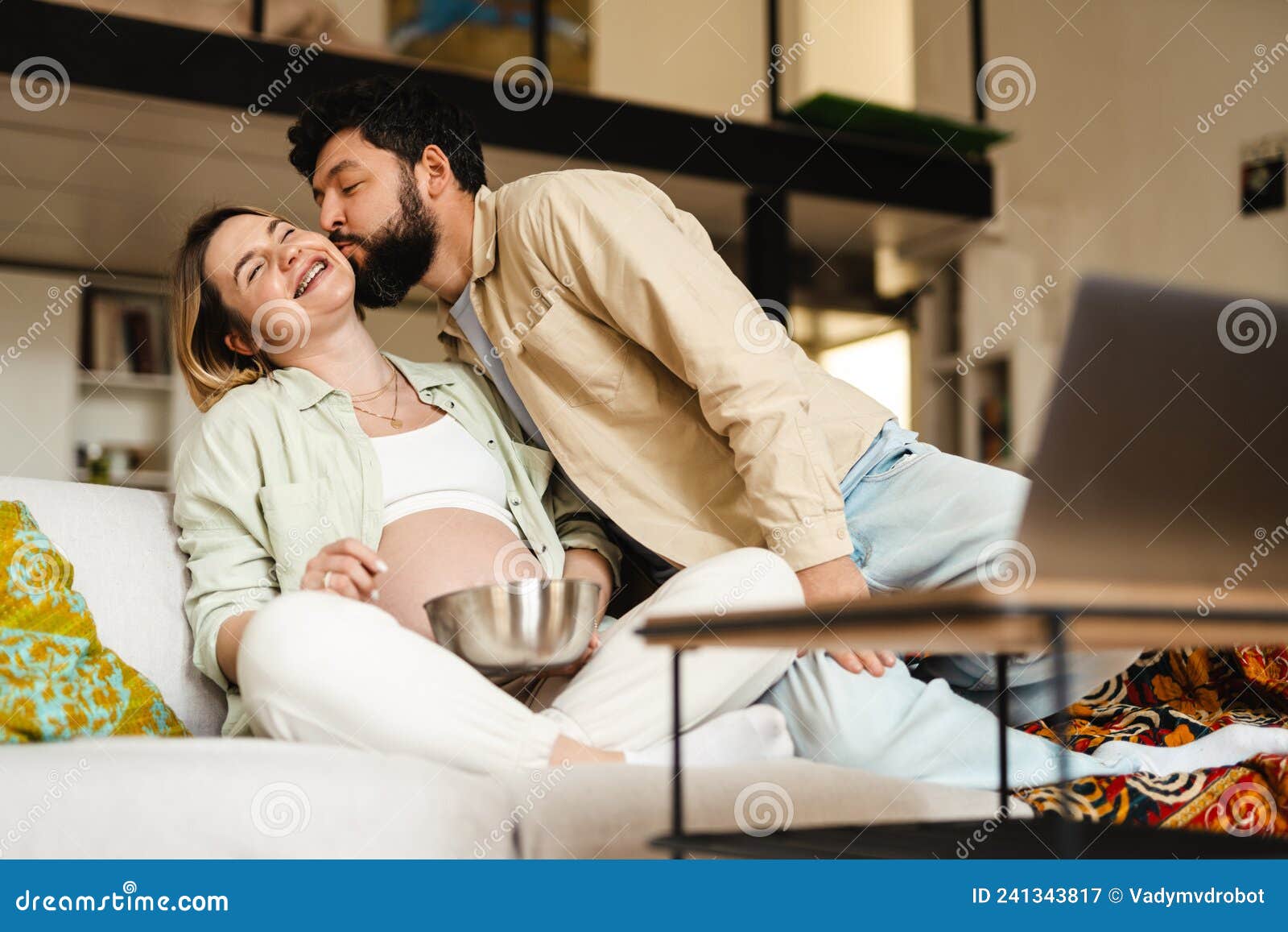White Man Kissing His Pregnant Woman while Watching Movie on Laptop Stock Image