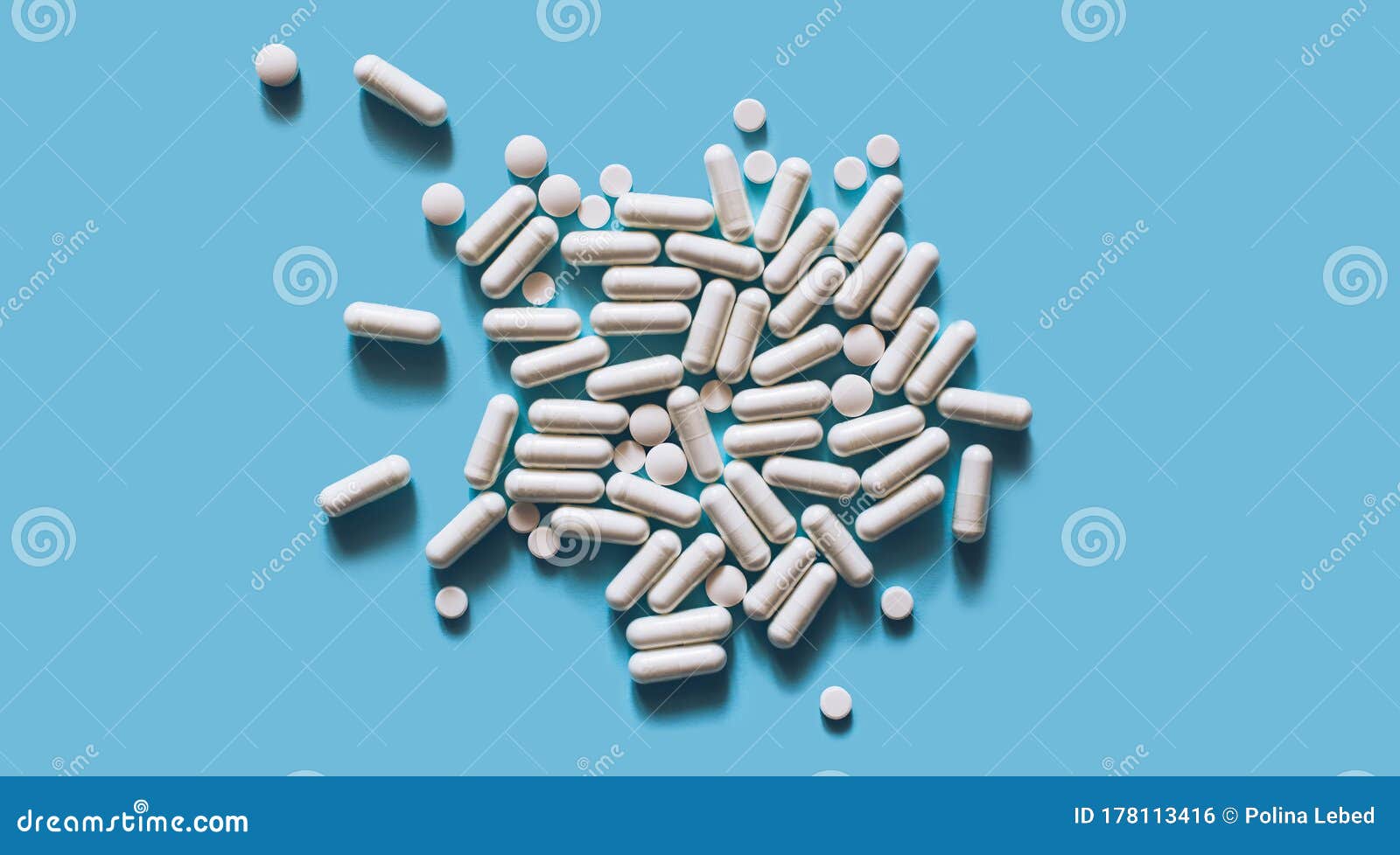 white medical pills and capsules or vitamines on blue background. copy space.