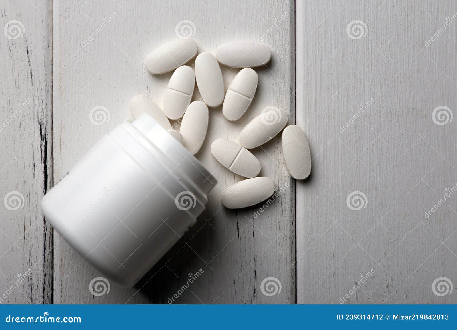 white pills with a jar on a wooden table