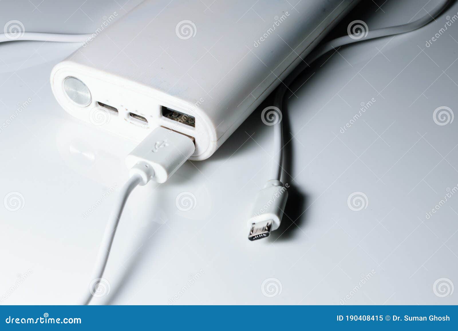 A White Power Bank with USB Ports and Power Button. a Cable is Attached