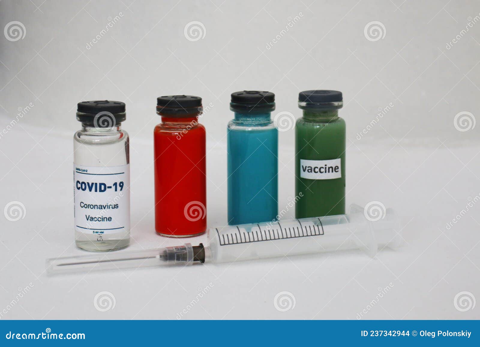 four ampoules with vaccine and medicines and a syringe on a light background.
