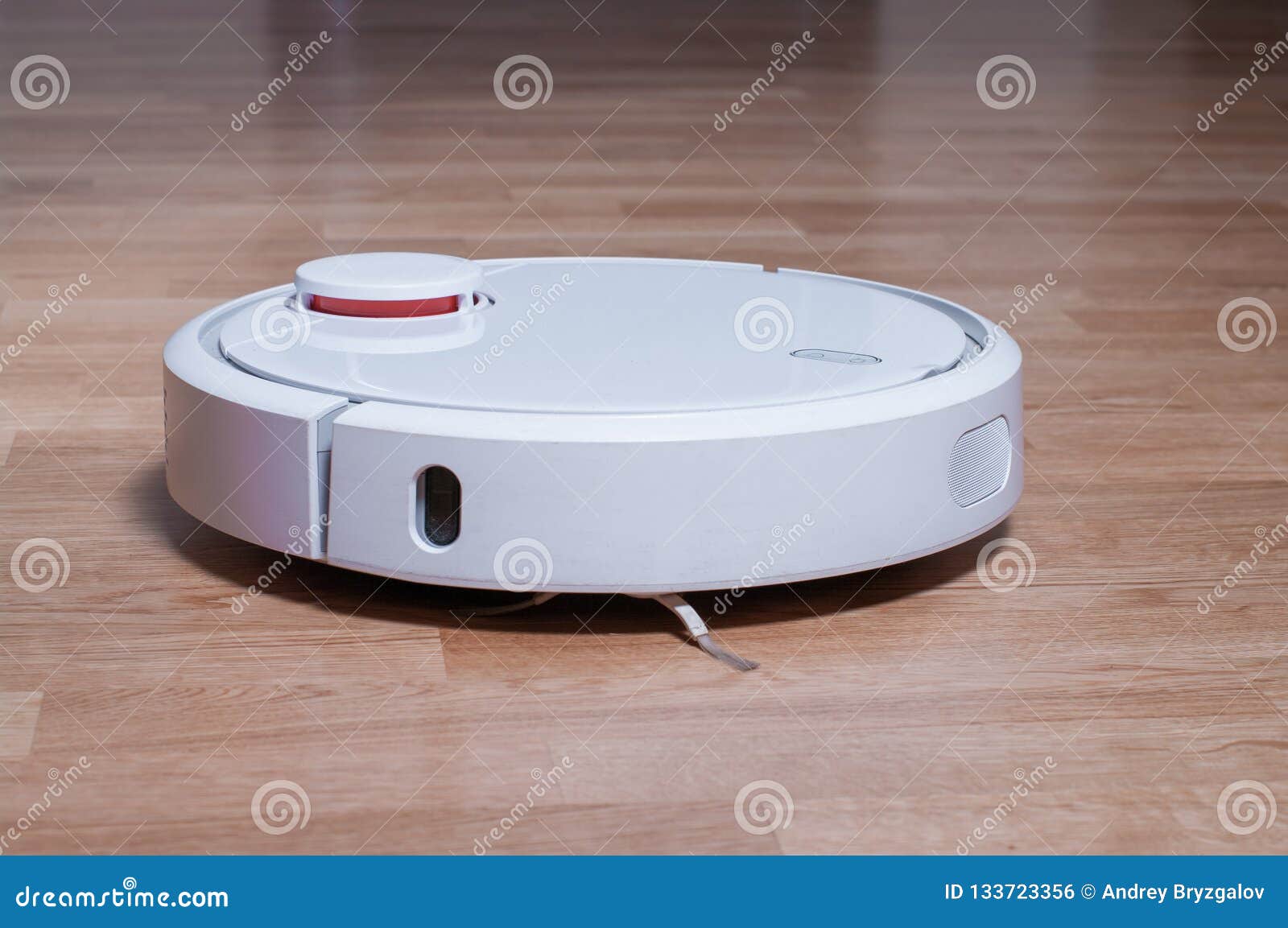 White Robot Vacuum Cleaner On Parquet Floor Cleaning Dust In The
