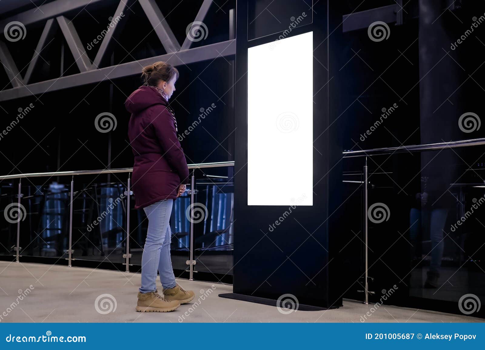 white screen concept - woman looking at blank interactive white display kiosk