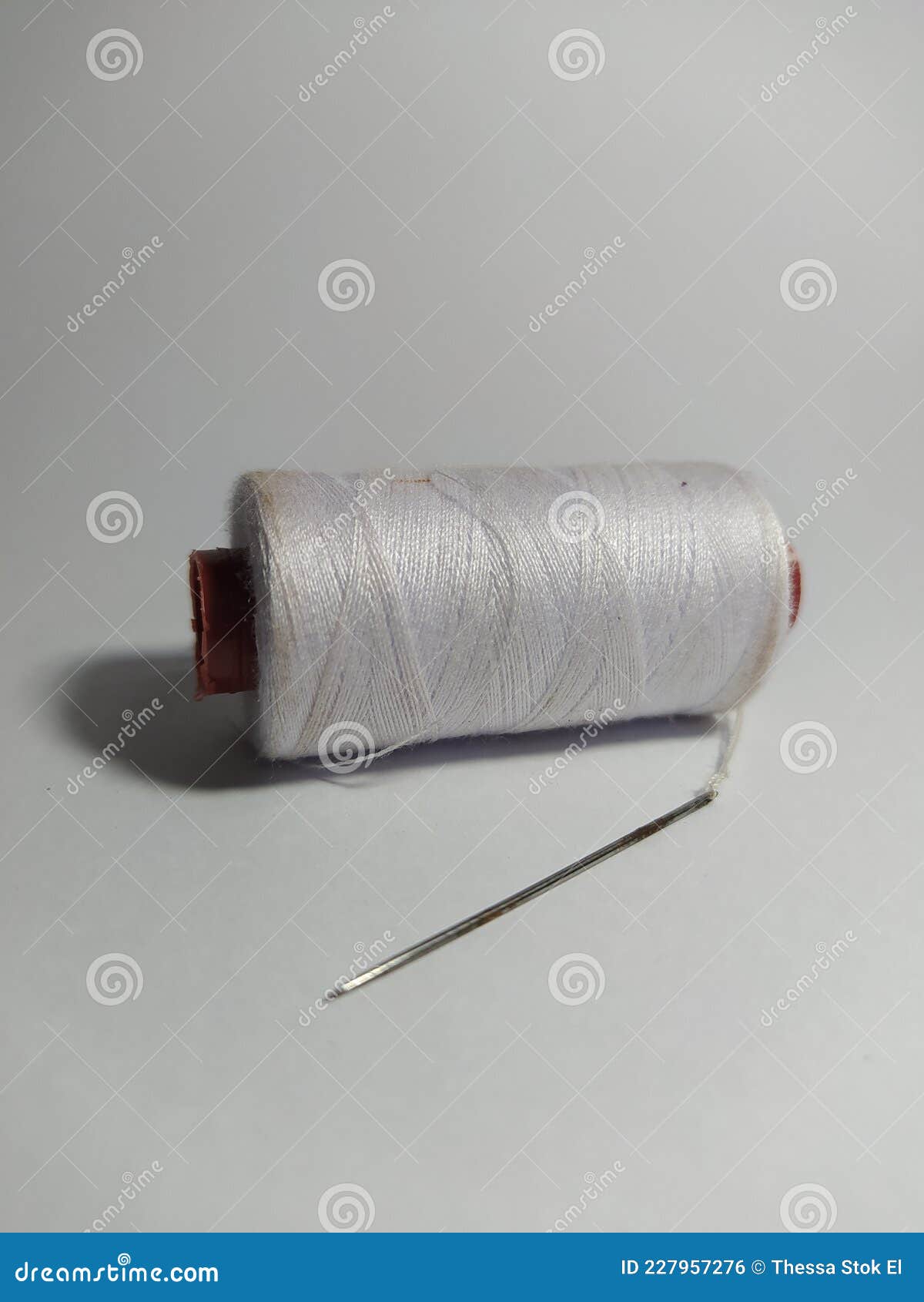 White Sewing Thread Spool and Needle. White Sewing Thread Stock Photo