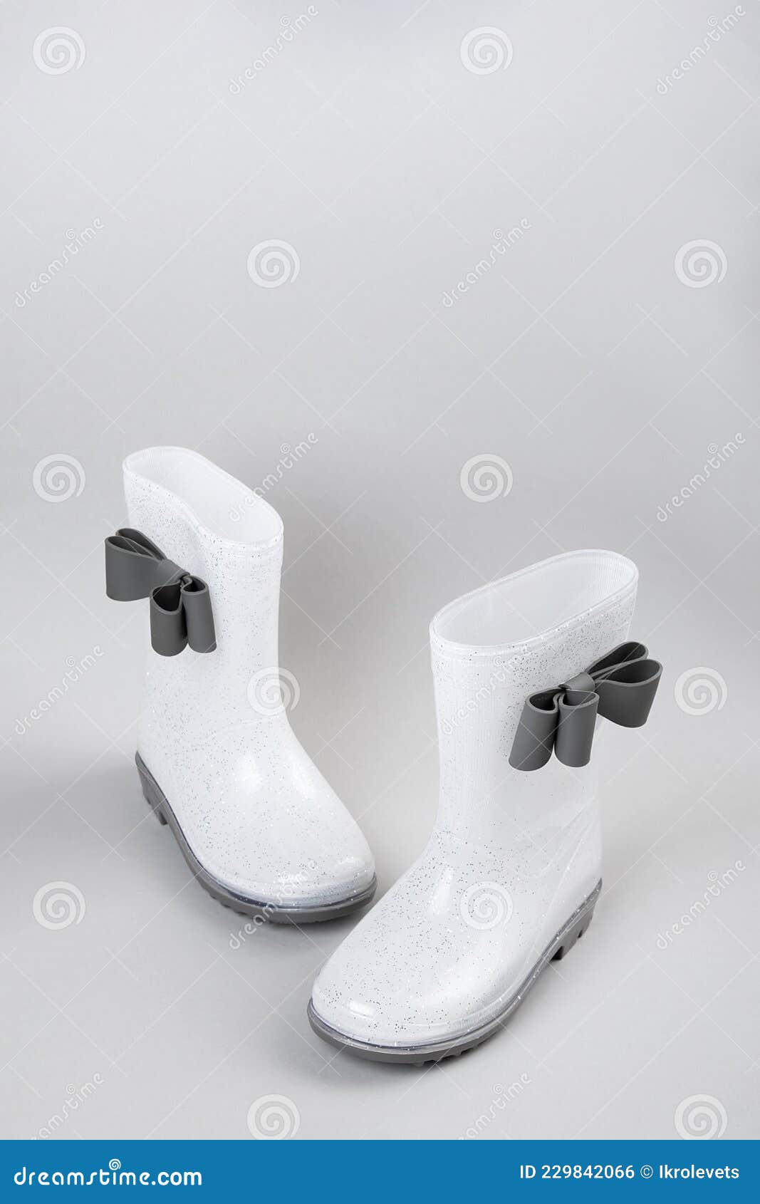 White Shiny Rubber Rain Boots with Bows on Gray Background with Copy