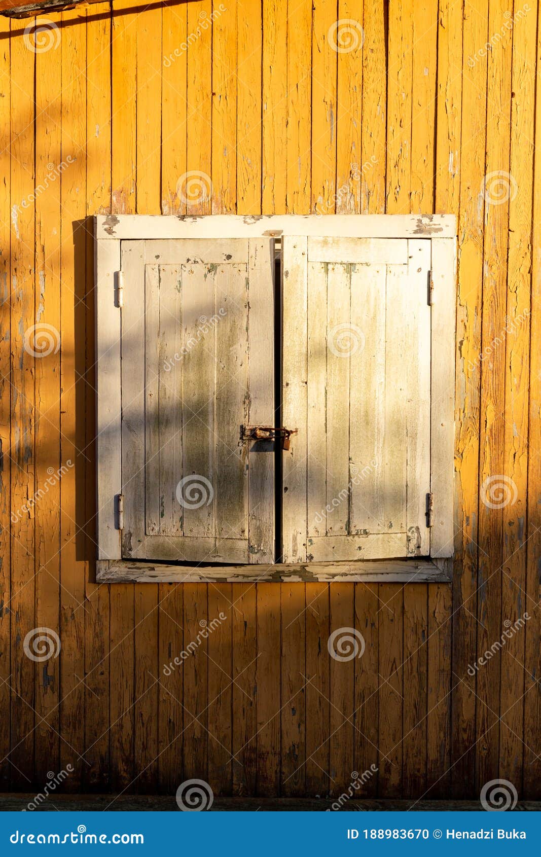 white shutters on a yellow house. closed window.