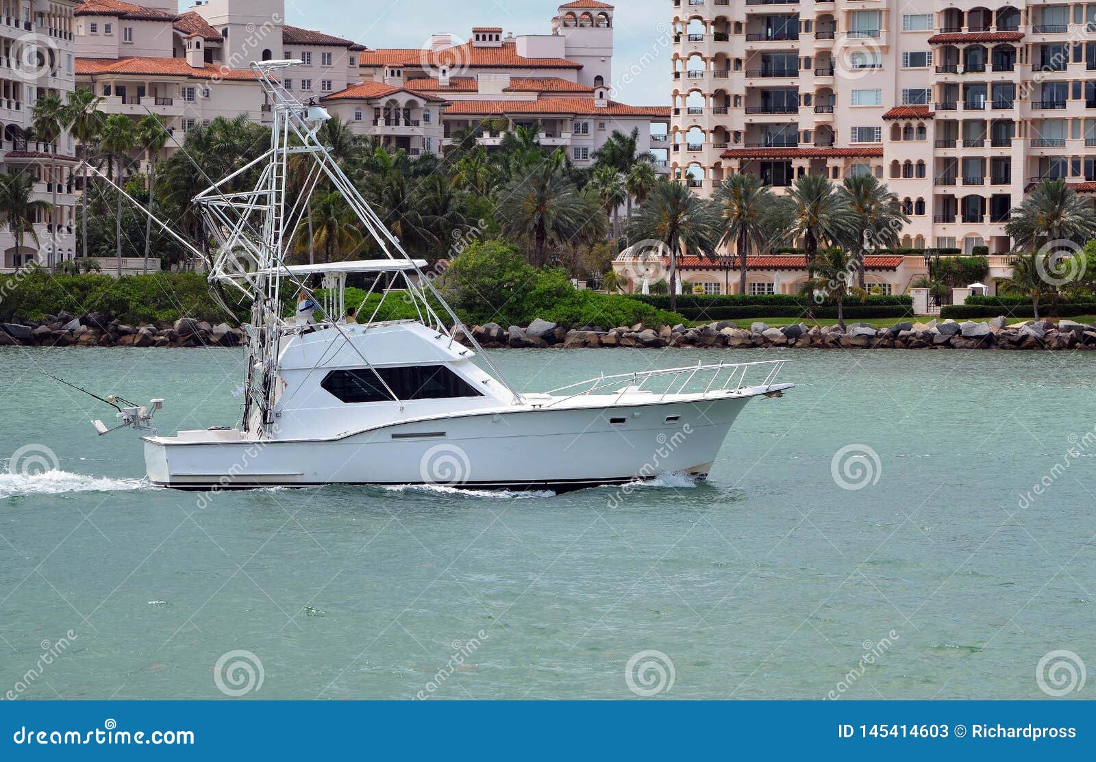 white sport fishing boat with flying bridge returning to port after a morning at sea.
