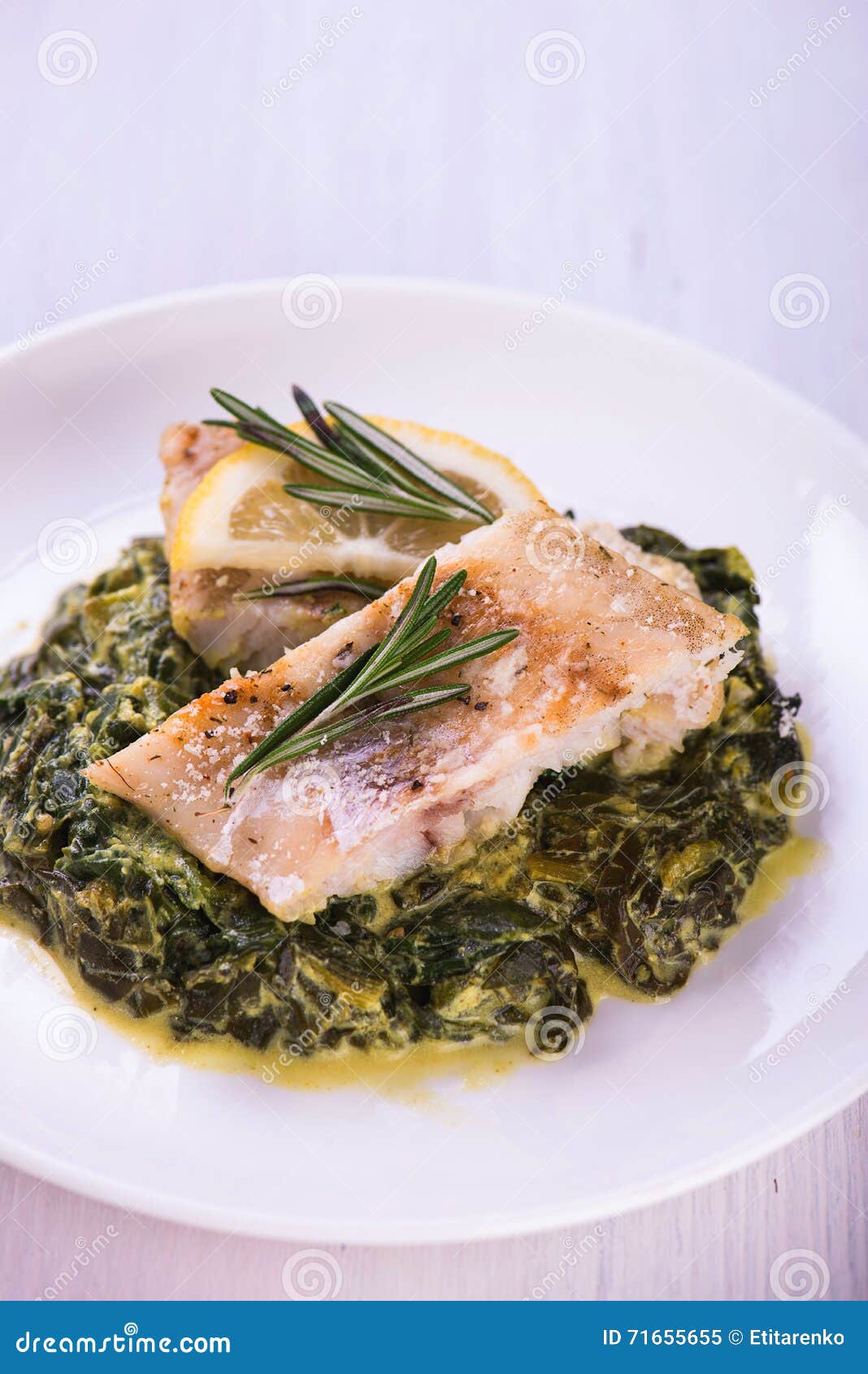 White Stewed Fish Fillet with Herbs on Fried Spinach Stock Image