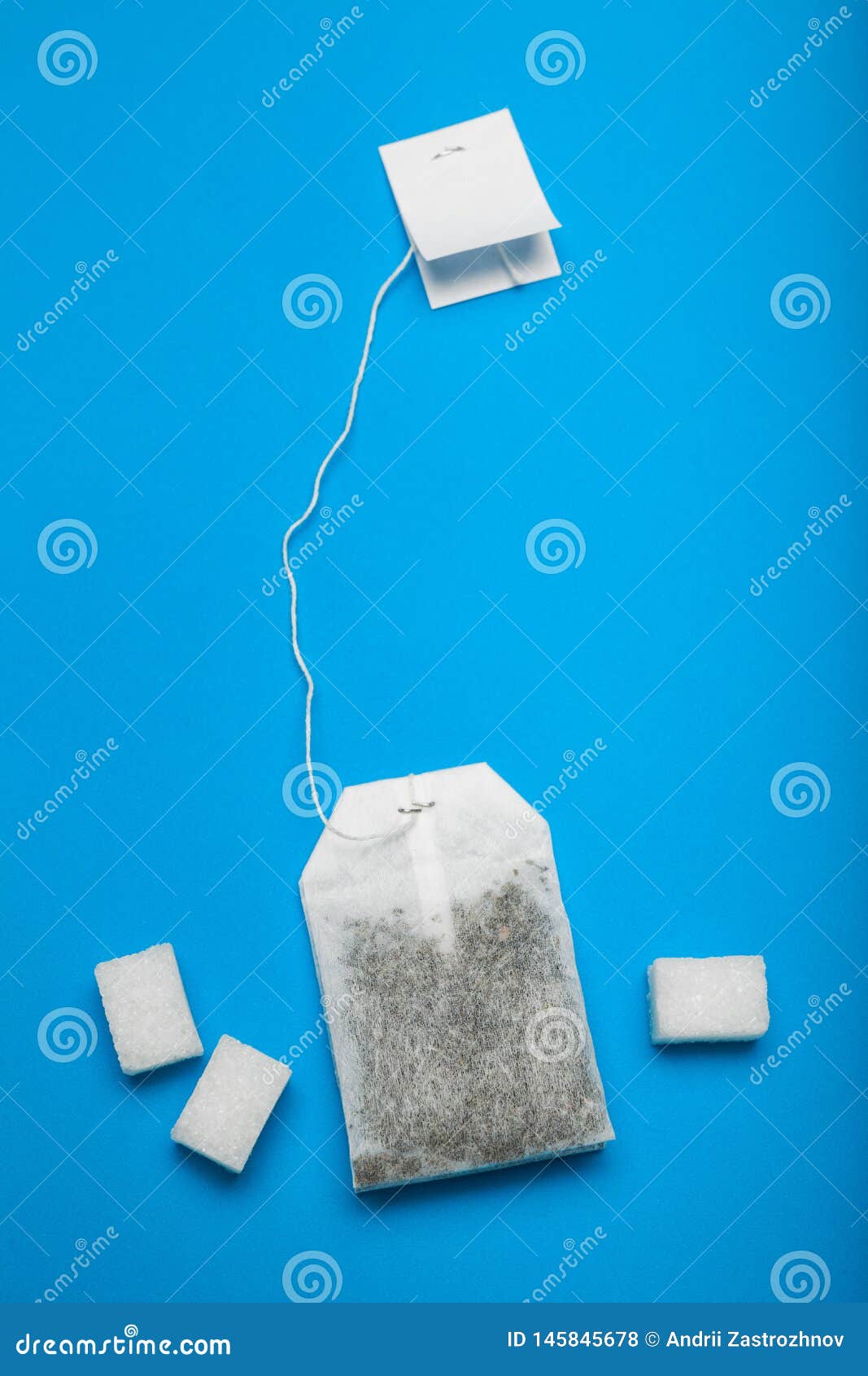 A White Tea Bag is Isolated on a Blue Background with Sugar Stock Photo