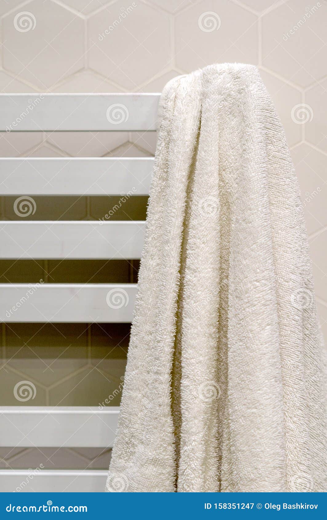 A White Towel Hangs on a Heated Towel Rail in the Bathroom Stock Image