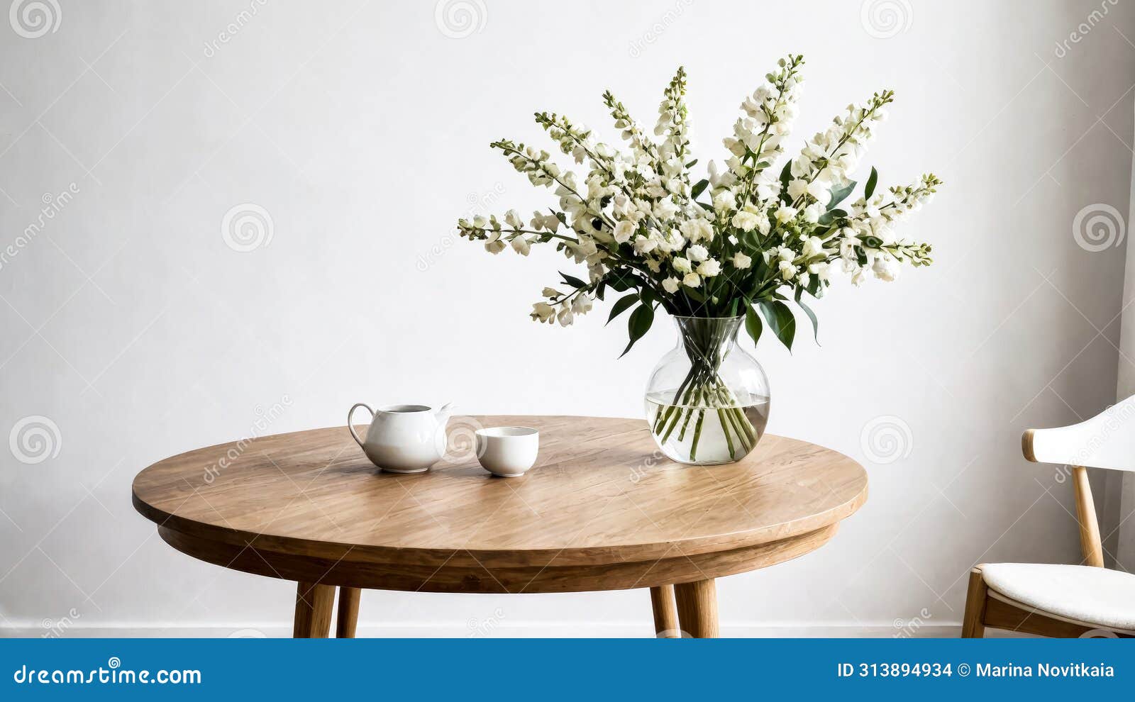 white wildflowers in paunchy vase on round wooden brown table against empty gray wall. minimalistic interior. scandinavian style