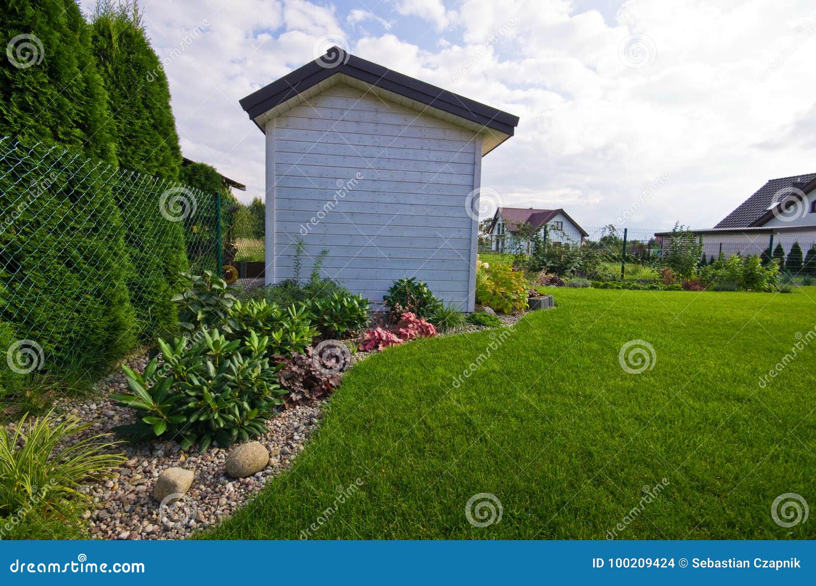 white wooden garden shed or hut with flowers and plants