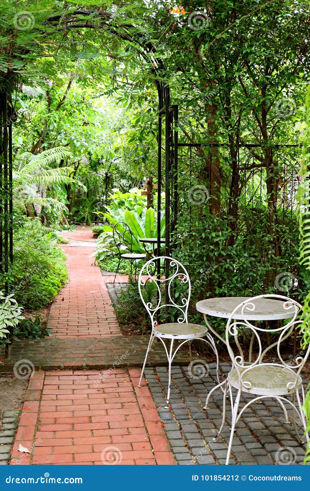White Wrought Iron Table and Chairs in the Garden with Bricks Paved