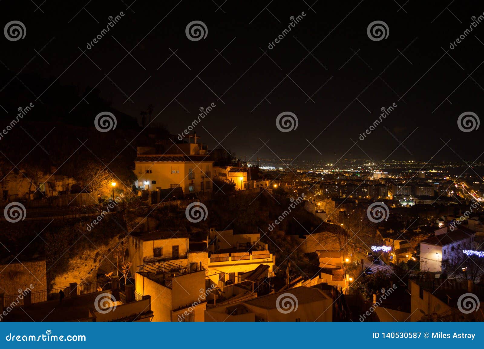 whitewashed houses and cityscape in granada, spain as seen from barranco del abogado at night