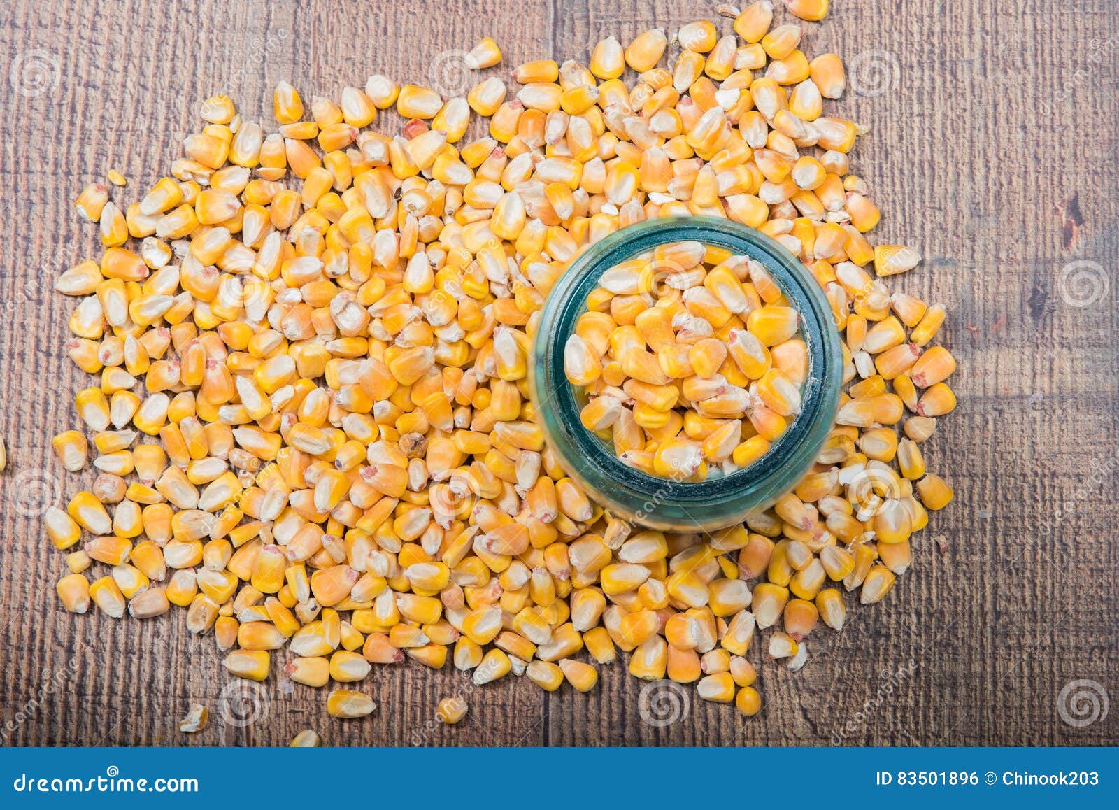 Whole Corn in a Jar with Corn Scattered Around it. Stock Photo Image