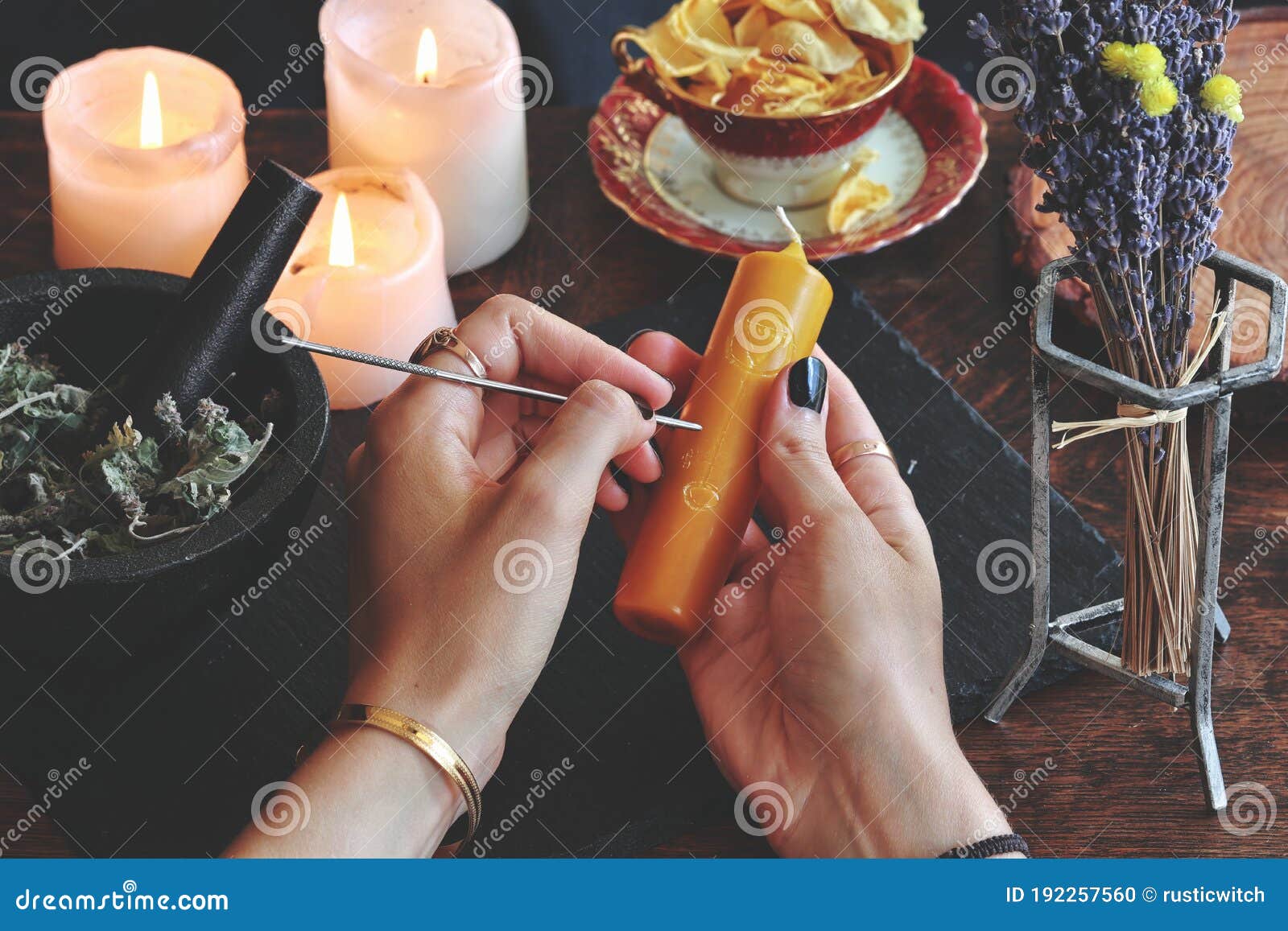 wiccan witch carving s and sigils onto yellow gold color candlestick at her altar