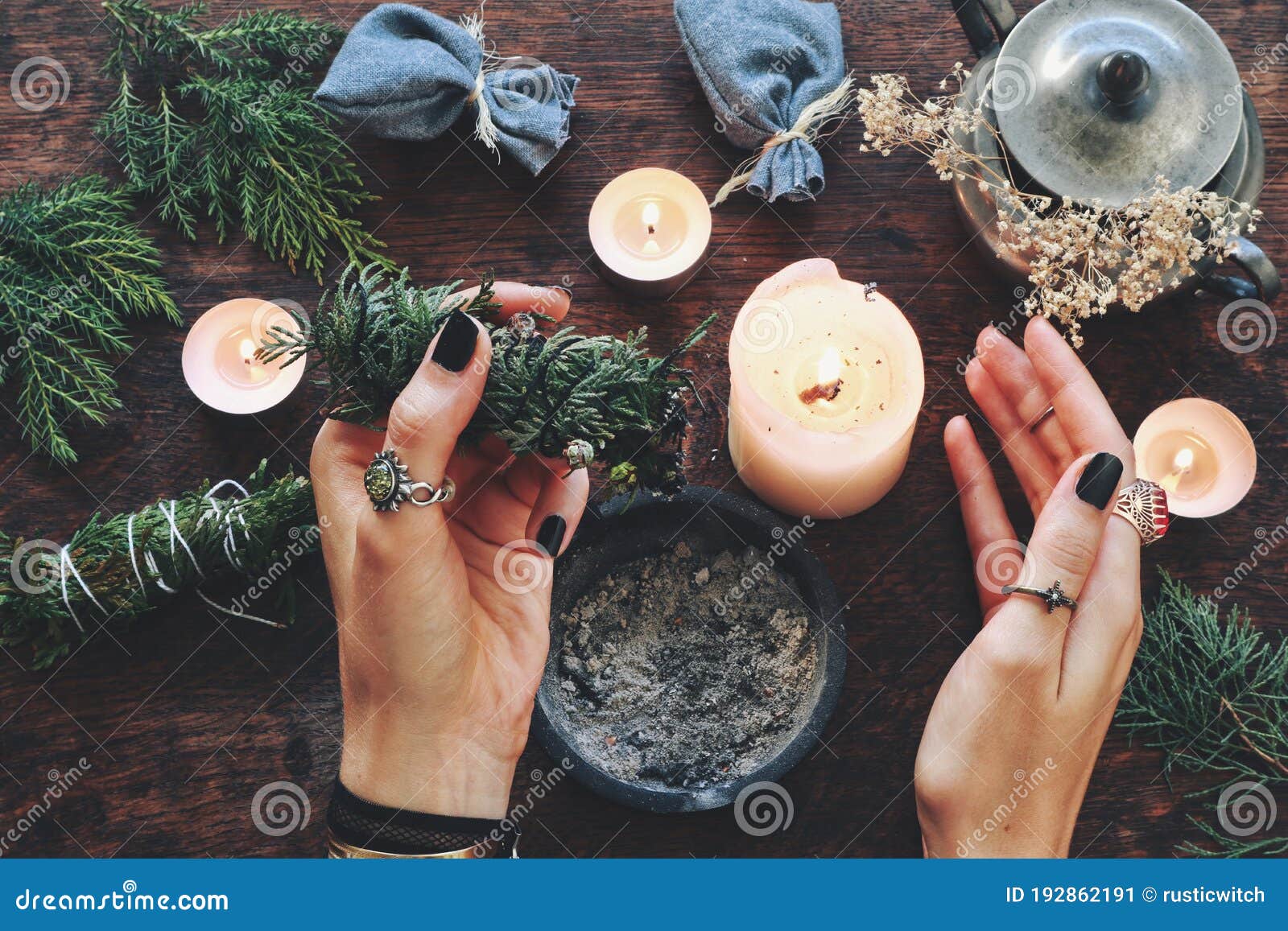 wiccan witch holding cedar cleansing stick to cleanse the energy at her altar