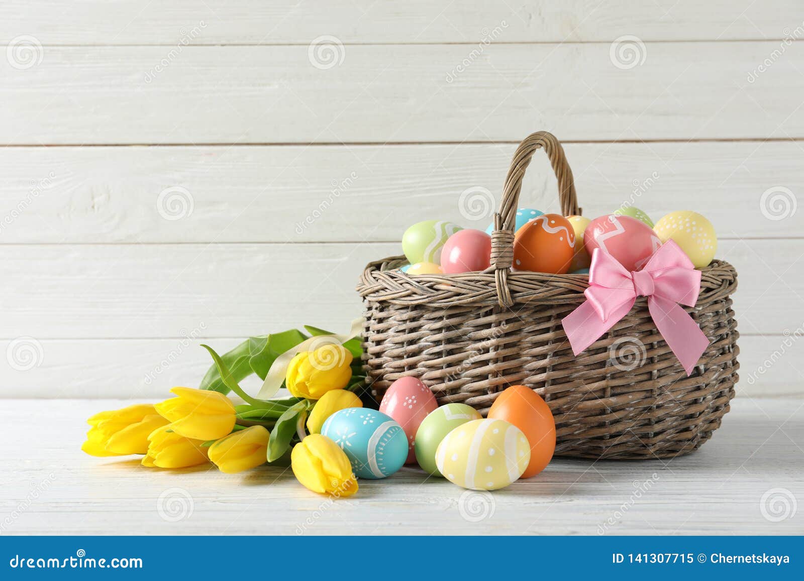 Wicker Basket with Painted Easter Eggs and Spring Flowers on Table ...