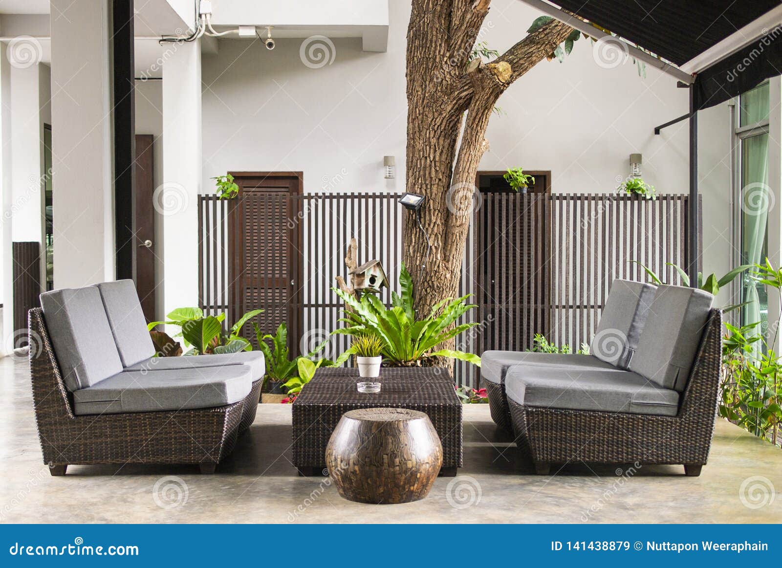 wicker sofa with pillows and table standing on garden terrace by the house