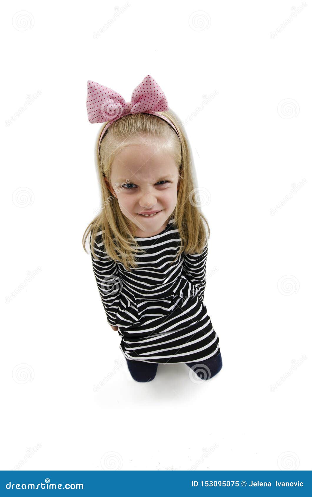 wide angle photo of a little girl shows her furrowed brow and irritated frown