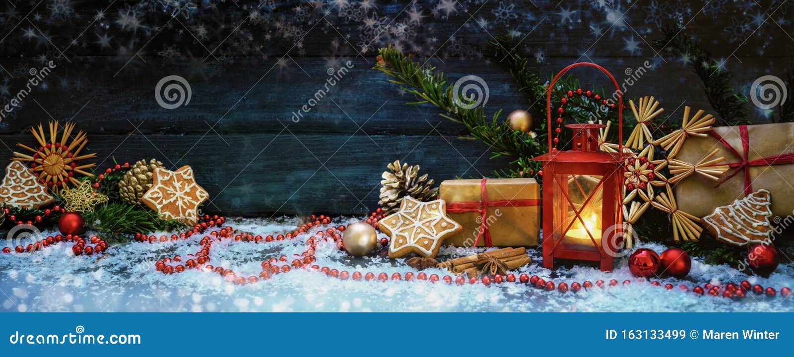 wide christmas background wit red candle light lantern, gifts, baubles and decoration, stars and snowflakes against a dark blue