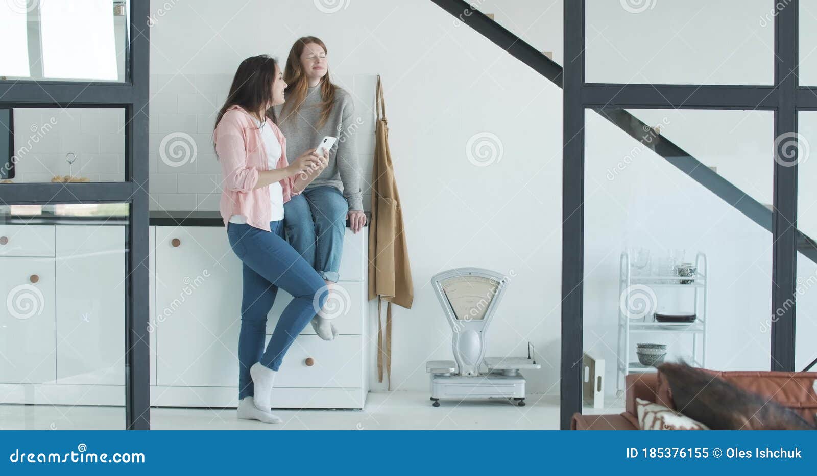 Wide Shot of Excited Caucasian Lesbian Couple Using Social Media on Smartphone