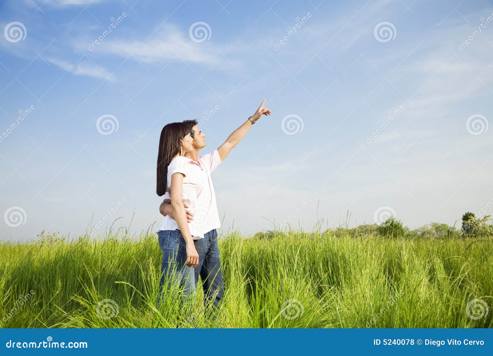 Junge Paare in der Wiese mit der Hand in einer Luft, umarmend. Kopieren Sie Platz