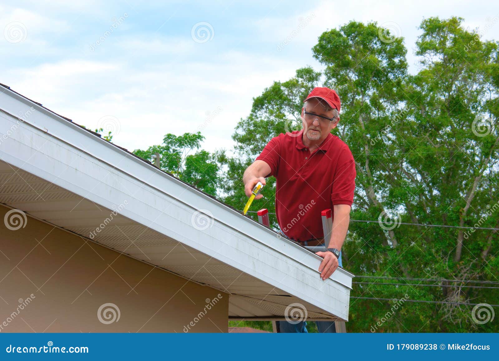 wind mitigation inspection inspector on a ladder doing inspection on new roof to generate a risk rating