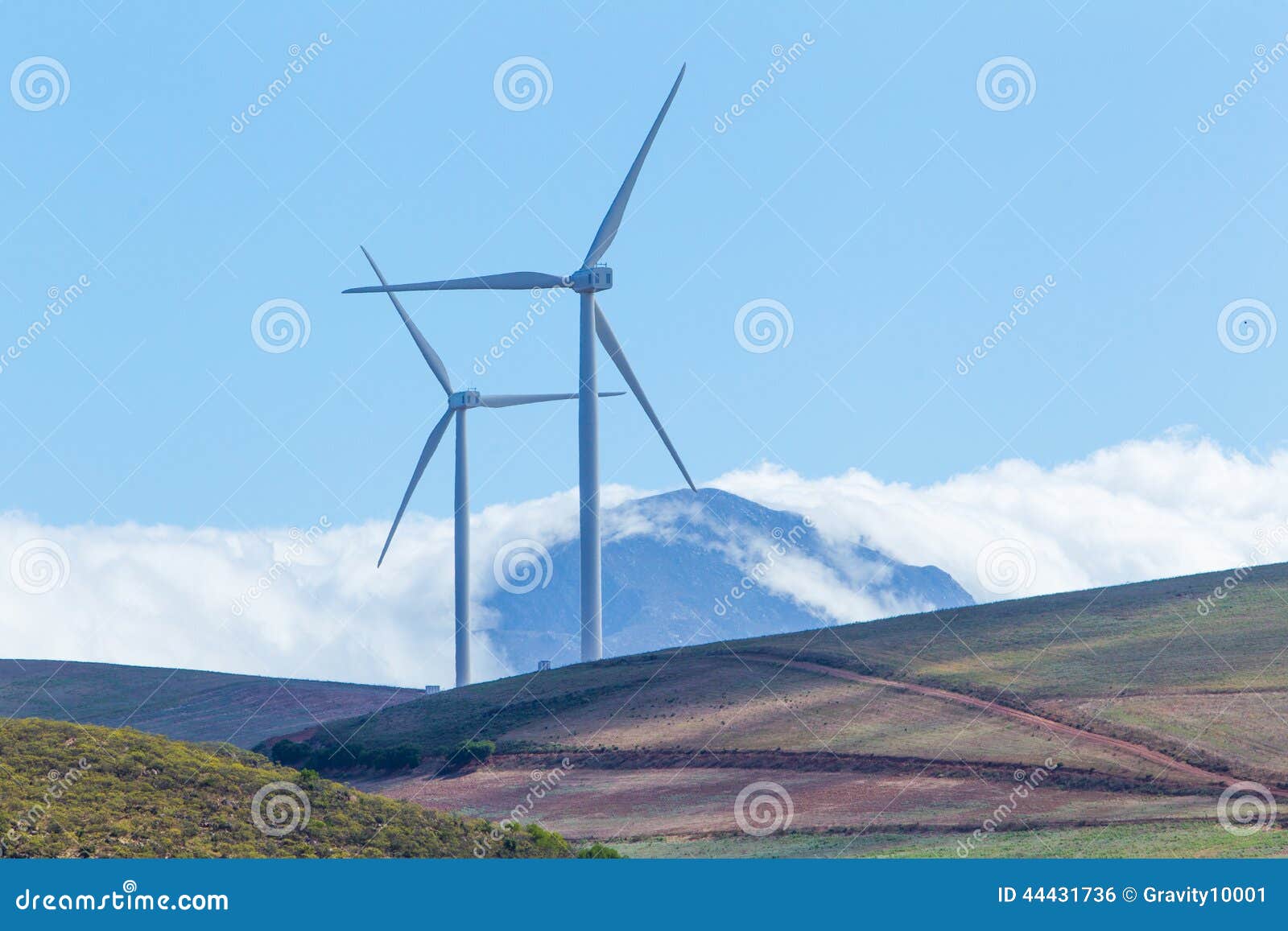 wind turbines with mountains and clouds in the background