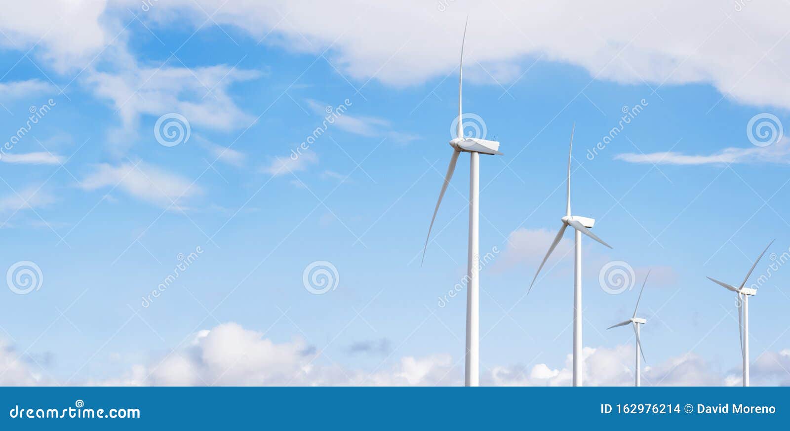 Windmills Rotating In Spanish Wind Farm Against Cloudy Sky. Copy Space