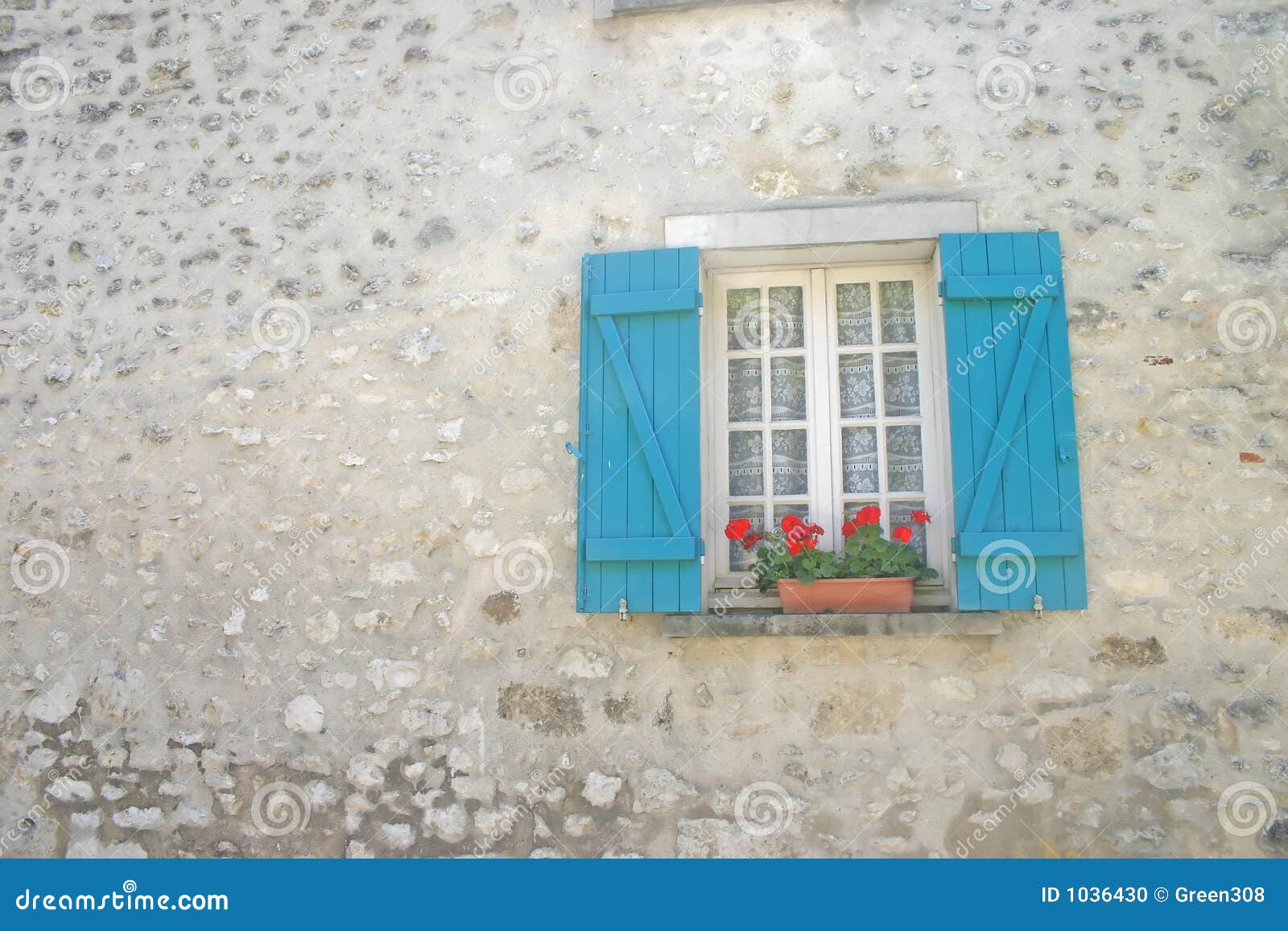 Window with Blue Shutters and Red Flowers in Stonebuilt Cottage Wall