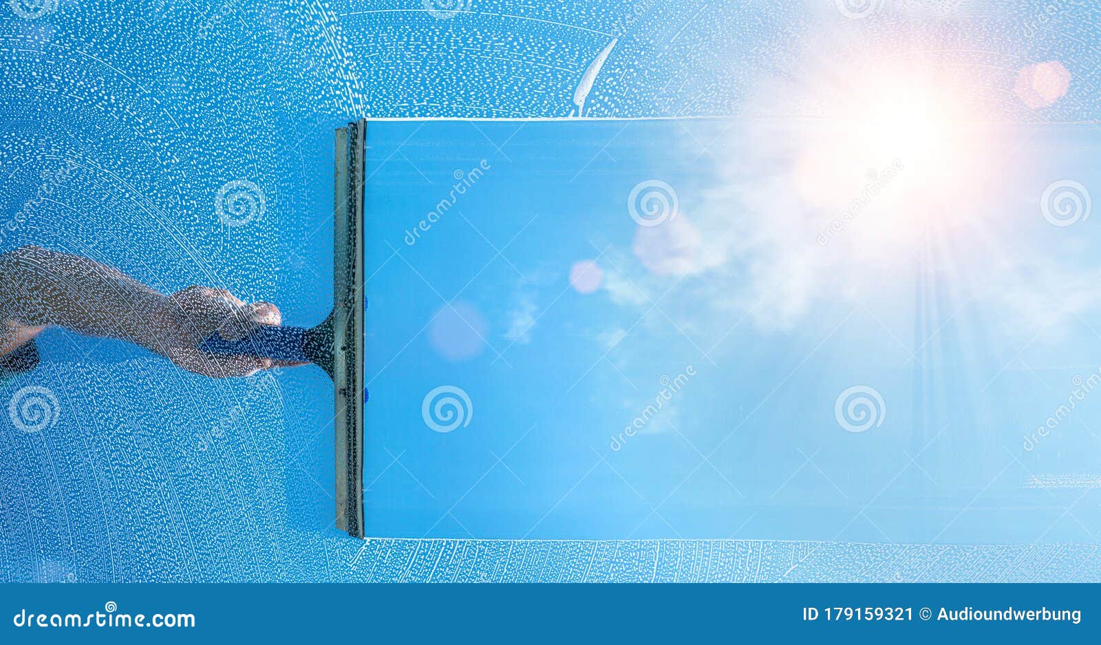 window cleaner cleaning window with squeegee and wiper on a sunny day