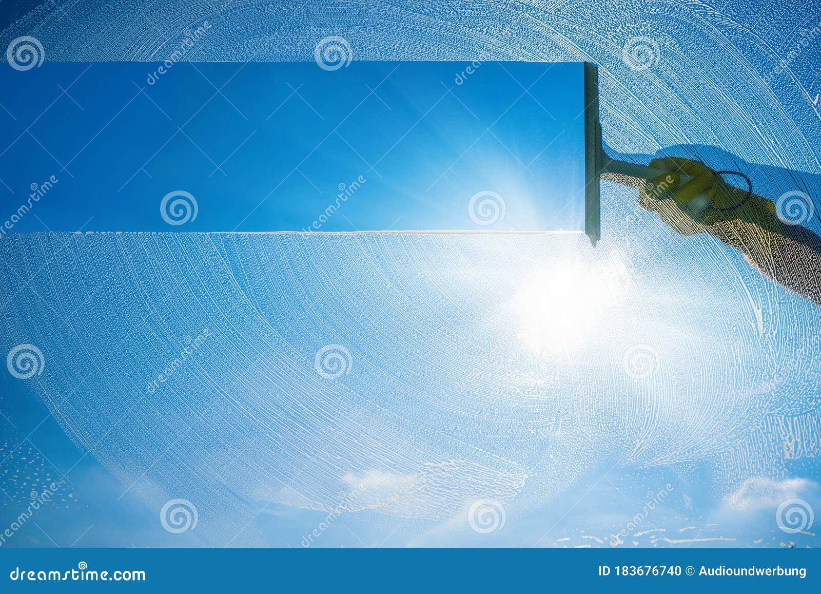 window cleaner cleaning window with squeegee and wiper on a sunny day with a bright blue sky