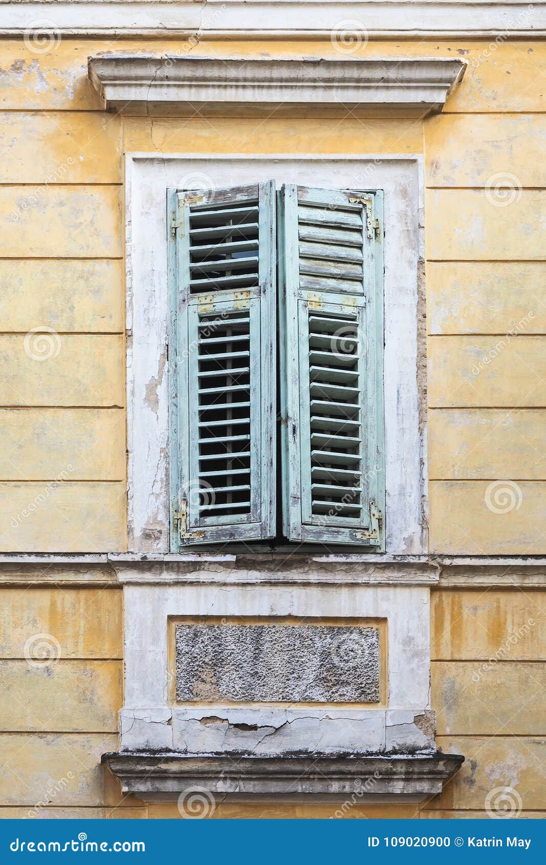 Window with Green Window Shutter in an Old Yellow House Stock Photo