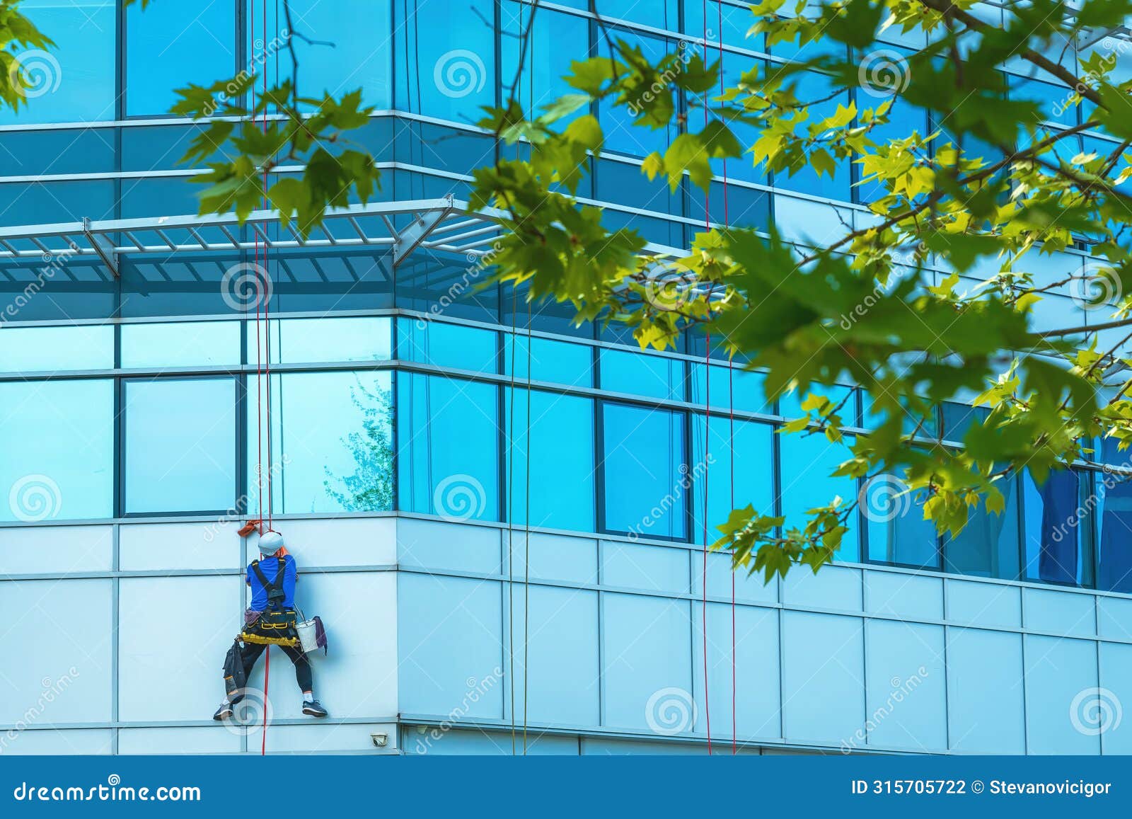 Window Washer Cleaning Facade of Modern Office Building Stock Photo