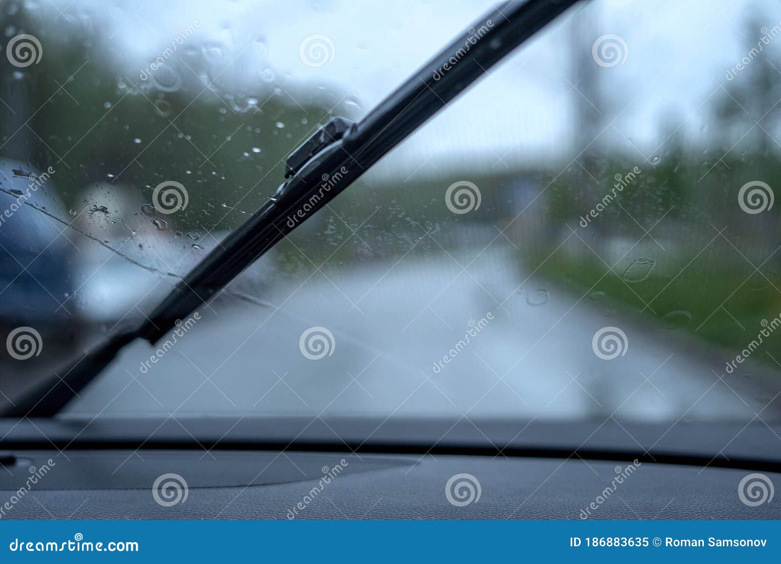 Windscreen Wipers Wipe Raindrops from the Windshield Against the Road