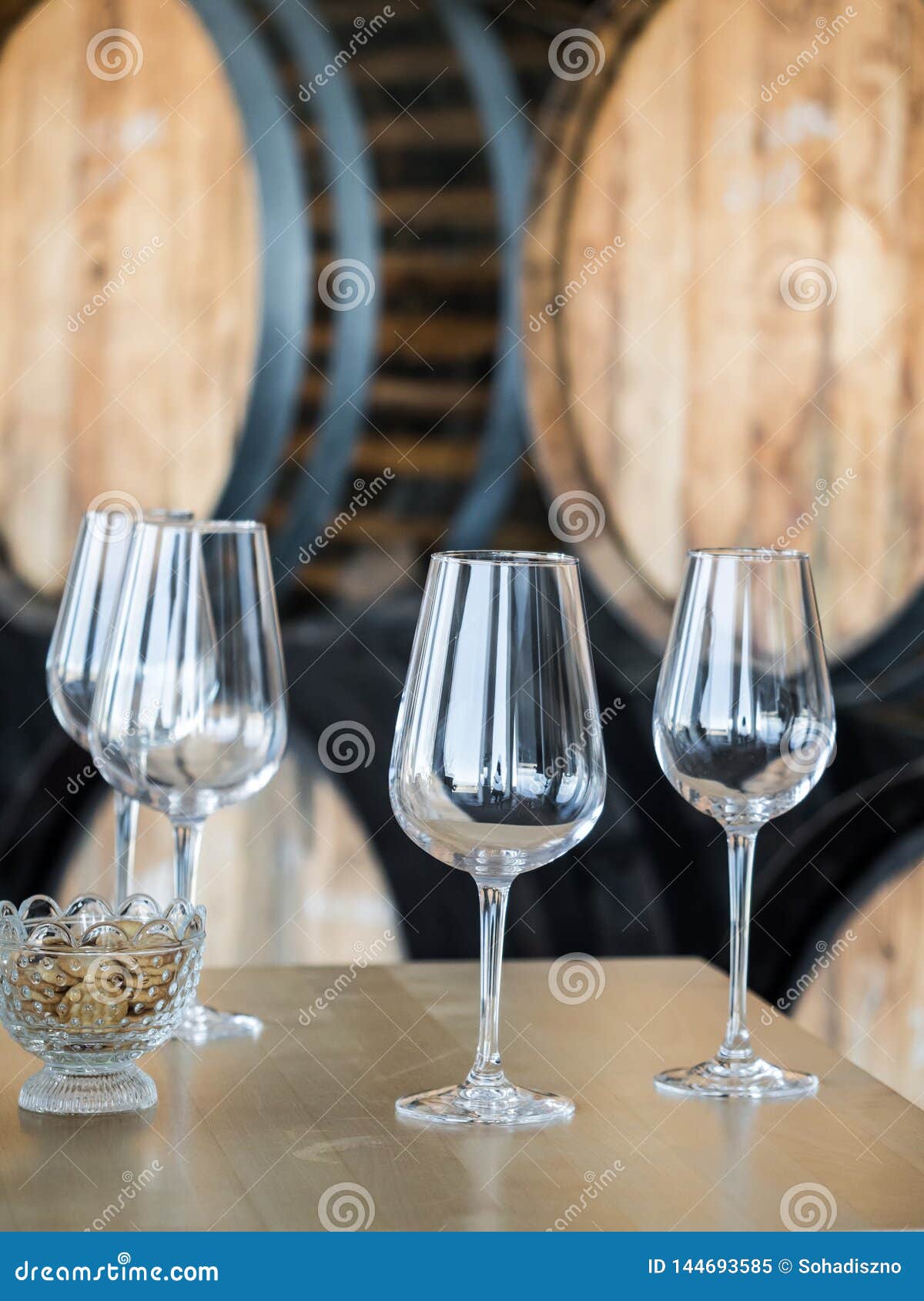 wine glasses in front of wooden wine barrels