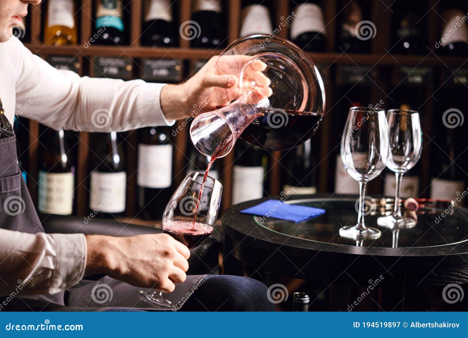 wine taster or degustator pouring red wine into carafe to make perfect color
