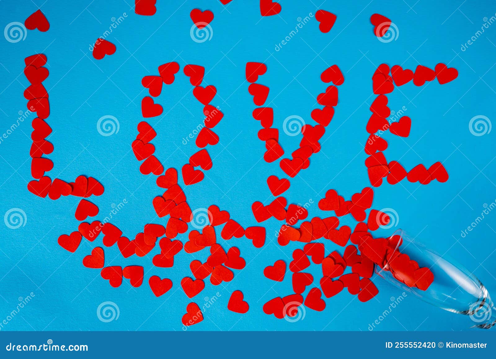 wineglass and word love from paper red hearts on blue screen background. top view of heart d confetti arranged