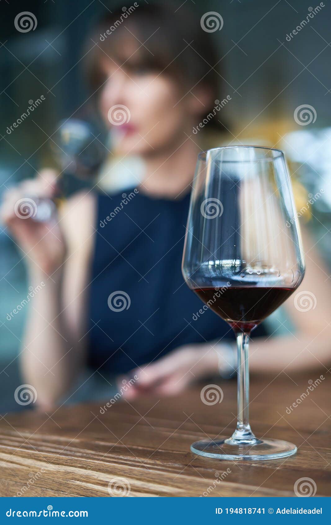 winetasting concept. focus on wineglass, woman drinking wine in the background