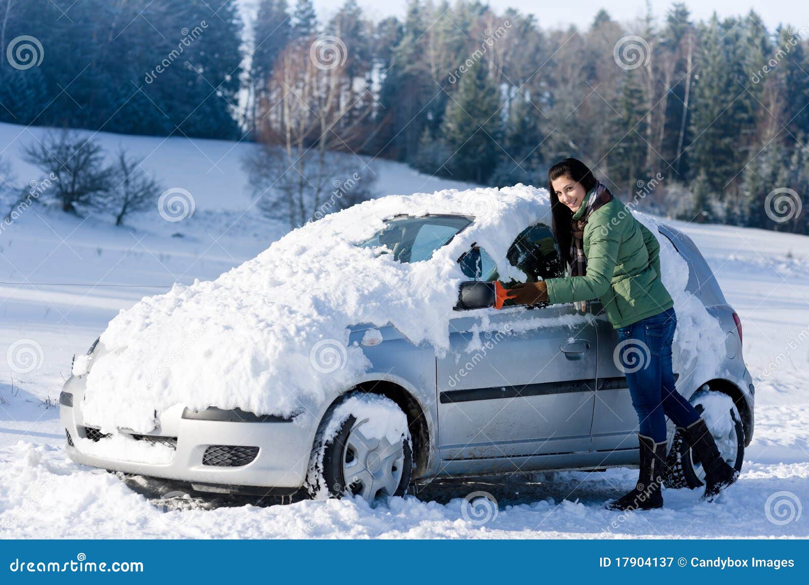 Winter car - woman remove snow from windshield with ice scraper