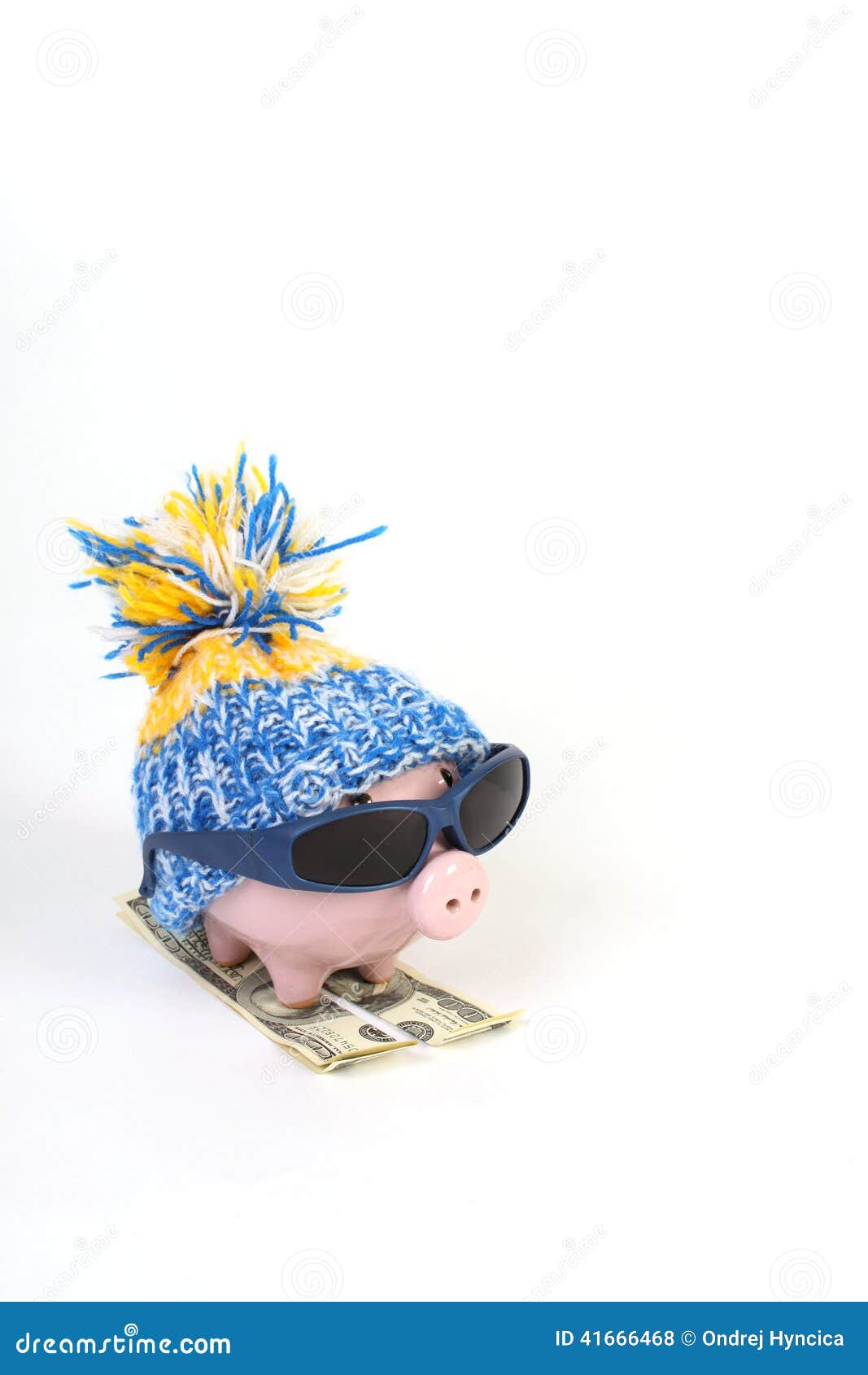 winter piggy bank with hat with pom-pom standing on skies of greenback hunderd dollars with sunglasses